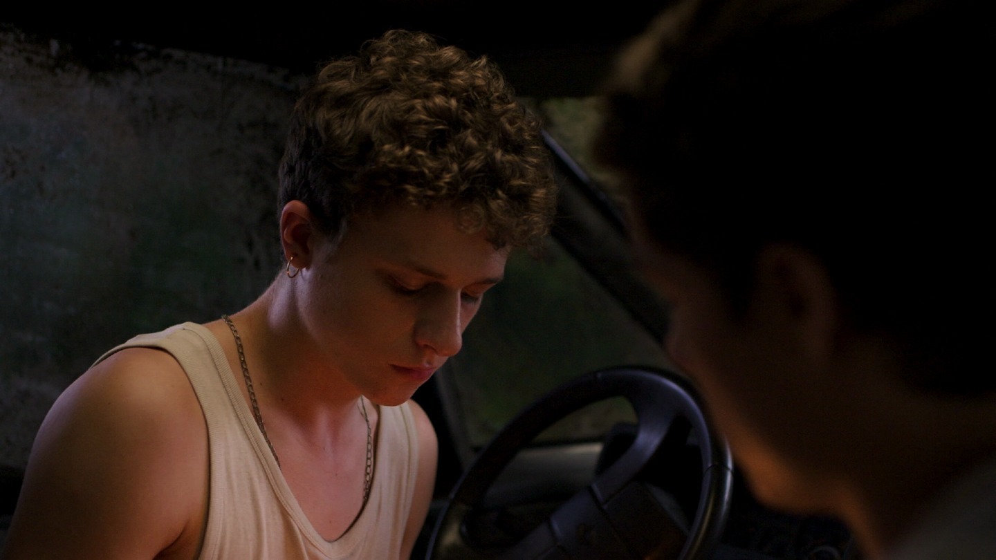 Simon baisse les yeux dans une voiture, face à Paul, dans Ruines.
